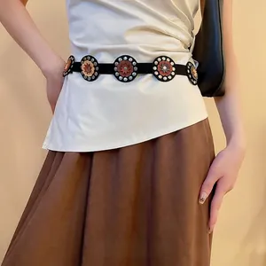 Bohemian leather belt featuring geometric floral circles and metal rivets over a silk shirt