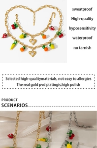 Detail of PVD gold plated jewelry set with enamel fruit charms and crystal heart pendant
