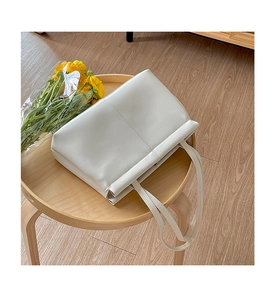 Top view of white minimalist soft PU leather tote bag on wooden stool with flowers