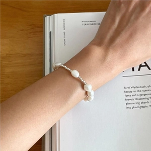Baroque pearl and silver bead bracelet shown on a wrist with minimalist aesthetic style