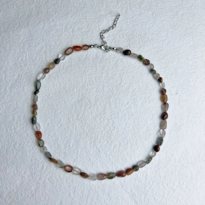 Macro view of multi-color irregular natural stones and stainless steel clasp of the necklace
