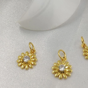 Detailed close-up of 14K gold plated daisy pendants with zircon crystals on silk