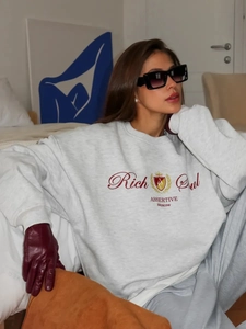 Λεπτομέρεια γκρι oversized φούτερ με κόκκινη στάμπα Rich Girl και street style ύφος