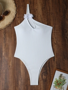 White one-shoulder one-piece swimsuit with floral detail and ribbed texture on wood background