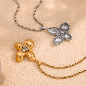 Close-up of 18K gold petal pendant with diamonds and silver floral necklace on beige fabric
