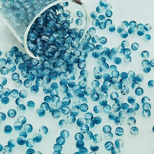 Dynamic view of blue and white crackle glass beads spilling onto a soft white faux fur surface
