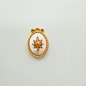 Macro shot of oval shell pendant with 18K gold plating and engraved starburst detail