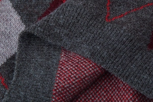 Macro detail of soft grey and red diamond pattern knit fabric with wool texture