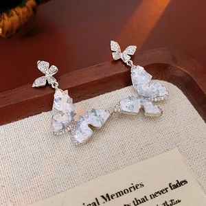 Dettaglio macro di orecchini a farfalla in argento con cristalli e pavé di diamanti