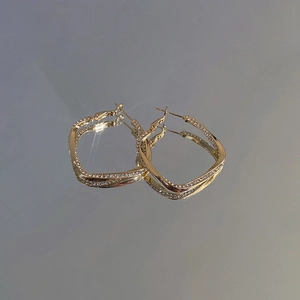 Detailed view of twisted gold hoop earrings with sparkling pavé crystal embellishments