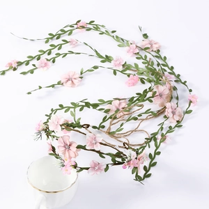Detailed view of bohemian floral headband with pink flowers and green leaves on white background