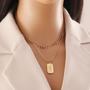 Collier double rang doré avec perles colorées et pendentif soleil bleu sur un mannequin