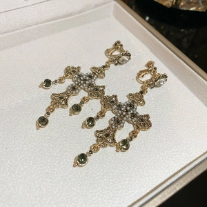 Detail of vintage baroque cross earrings with pearls and green gemstones on white box