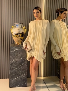 Détail de la robe beige avec textures plissées élégantes et un style d'ourlet bouffant