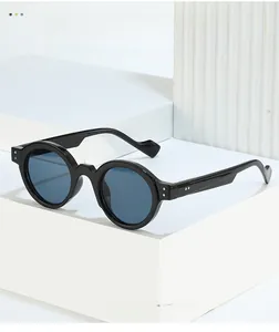Detail of black round steampunk sunglasses with silver rivets on a white pedestal