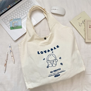 Close-up of beige canvas tote bag with cute astronaut rabbit print and snap button