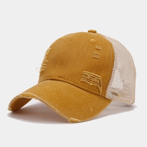 Close-up of distressed mustard yellow cotton and beige mesh baseball cap with ripped details