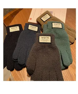 Close-up of five pairs of warm knitted gloves in assorted colors with stitched warm labels