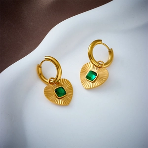 Gold striped heart earrings with green zircon pendant on white decorative base