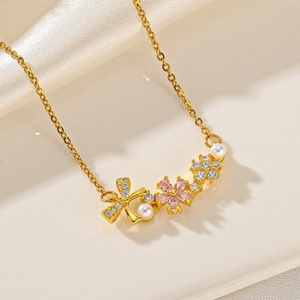 Elegant gold butterfly necklace with pink crystal flower and pearls on silk background