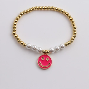 Bracelet perlé avec perles dorées, perles blanches et charmant smiley émaillé rose