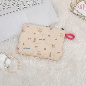 Detailed macro view of cream quilted cosmetic pouch featuring cute cartoon animal patterns