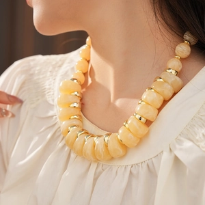 Gros plan d'un collier vintage à grosses perles jaune crème avec intercalaires dorés
