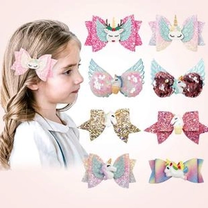 Detail of glitter unicorn bow hair clips and rainbow wing accessories for girls