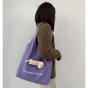 Detail of purple canvas tote bag with 3D plush cat ornament and white letter embroidery