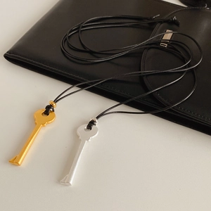 Détail de pendentifs clés dorés et argentés avec cordons noirs sur du cuir