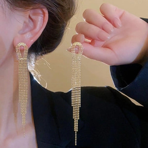 Detailed view of long gold tassel earrings with metallic bead chain texture in hand