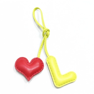 Handmade leather bag charm with red heart and yellow 3D letter L on white background