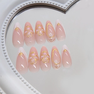 Elegant almond press-on nails with French tips, gold floral art and star patterns