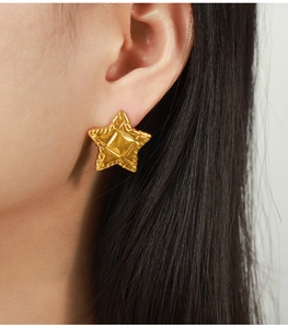 Gros plan sur les boucles d'oreilles étoile dorée 18 carats avec texture en relief