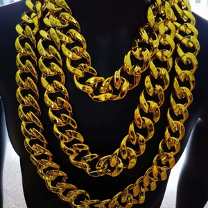 Macro detail of thick gold-plated chunky Cuban link necklaces on a black mannequin torso