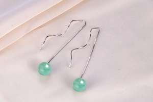 Detail of S925 silver ear wire with green aventurine bead on white silk background
