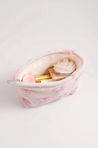 Detailed view of pink plush makeup bag featuring heart texture and silver zipper