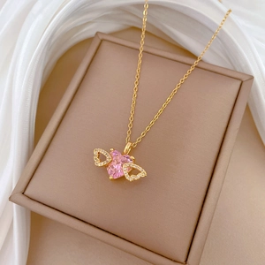 Detail of gold necklace with pink heart gem and angel wings in a gift box