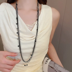 Detail view of multi-layered long necklace featuring black and silver glass beads