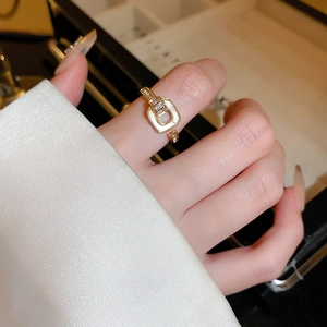 Close-up of gold geometric square ring with white enamel inlay and zircon accents
