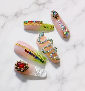Detailed view of snake-shaped nail charms with zircons and rose gold plating accents