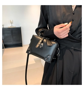 Detail of black gothic crossbody bag featuring silver skull emblem and metallic rivets