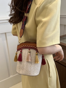 Detail of woven bucket bag featuring colorful tassels and ethnic geometric wide strap