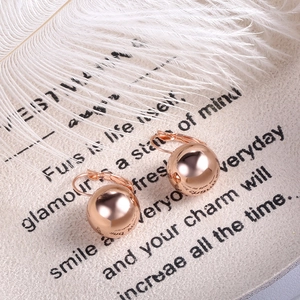 Close-up of rose gold ball earrings with leverback closure on a decorative tray