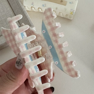 Detail of pink plaid and floral bow hair claw clip showing teeth and metal spring