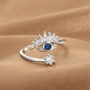 Silver evil eye open ring with blue stone and white cubic zirconia on brown fabric