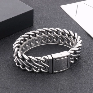 Macro detail of silver stainless steel thick Cuban chain bracelet with rectangular clasp