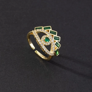 Detail of gold evil eye ring with green gemstones and adjustable open band design