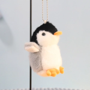 Close-up of cute penguin plush keychain with orange beak and metal bead chain