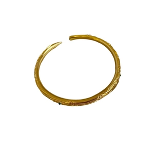 Vintage gold open bangle with embossed vine patterns and green gemstone accents